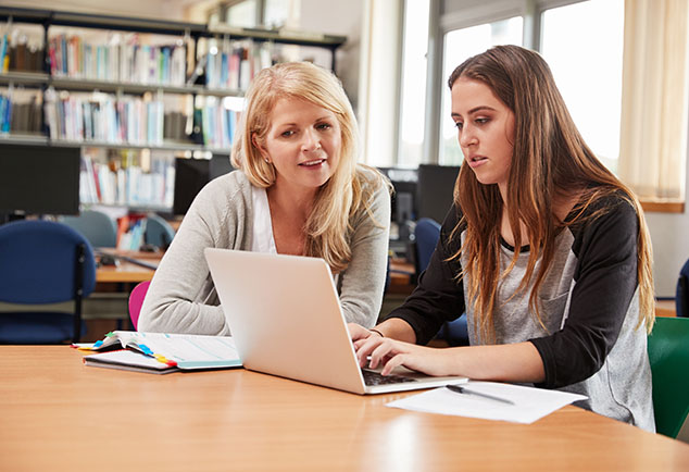 teacher supporting student on laptop 